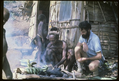 Food preparation: Roy Rappaport observes Muk cooking bananas, Rappaports' house in background