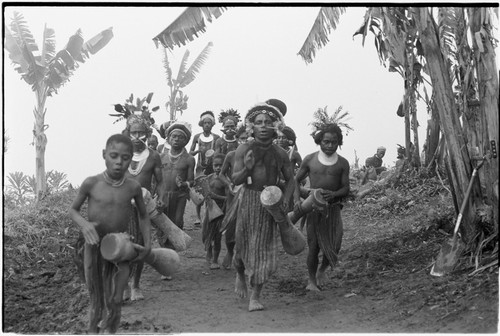 Pig festival, singsing: men and boys sing and play kundu drums on way to dance ground