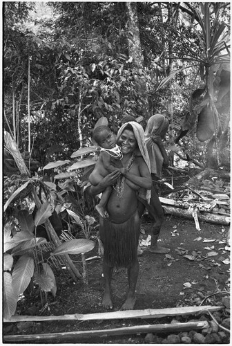 Pig festival, pig sacrifice, Tsembaga: woman and young child, fire in background