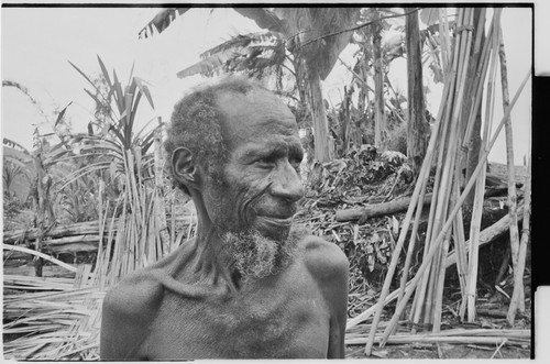 Older man with beard, woven wall panel and other building materials in background