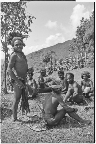 Men on grounds of government rest house in Tsembaga, one holds small pig