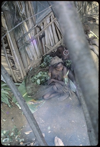 Women sit beside Rappaports' house, garden produce in netbags