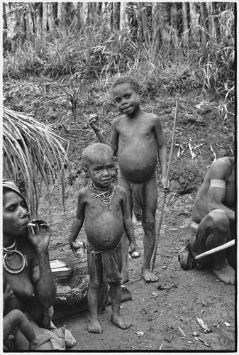 Smoking woman with netbag of firewood, two children