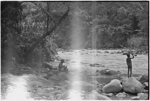 Simbai River Valley: men and boy relax on bank of a large river