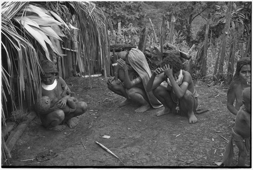 Women breastfeeds infant in house yard