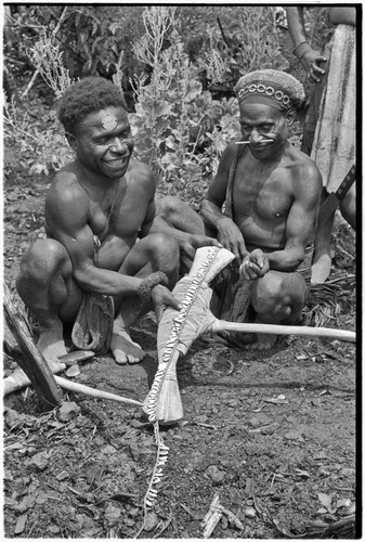 Ritual exchange: men measure strand of cowrie shells against blade of stone axe