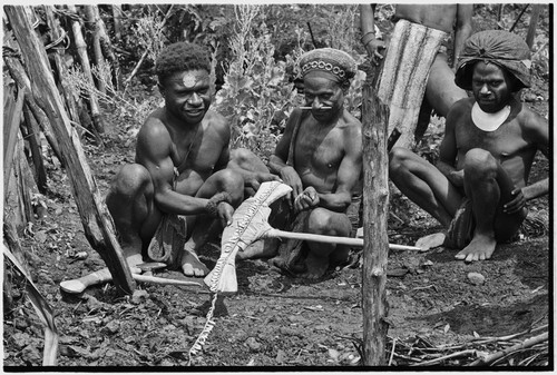 Ritual exchange: men measure strand of cowrie shells against blade of stone axe