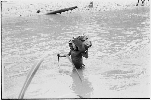 Schrader Range: man carries cargo across Anjimamp River between Korumbon and Ambaiat