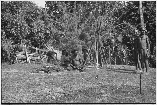 Men on grounds of government rest house in Tsembaga, their bows and arrows propped beside them