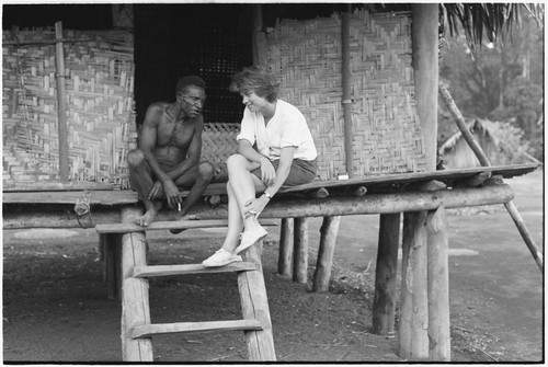 Ambaiat: Ann Rappaport and luluai Ankeginjginj talk and smoke cigarettes on steps of raised house