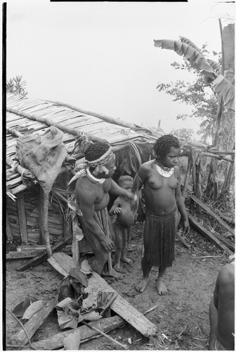 Bride price ritual: man placates woman, frightened child behind them, leaf bundle with valuables on left