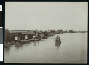 Small boat coming down the river in Sacramento, ca.1900