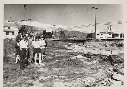 Class of children with teacher (?) surveying the effects of the flood