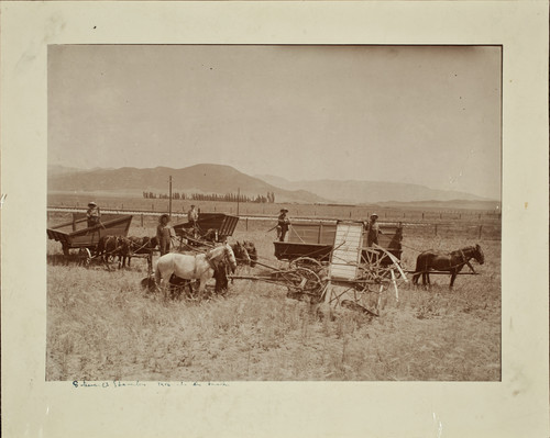 Stewart Ranch; men with horses and thrashing machines. Looking south with the railroad, Stewart Ranch, and the mountains in the background