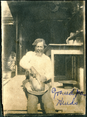 Wiley Hinds sitting on front porch cutting watermelon