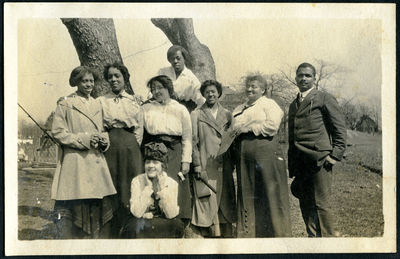 Nine men and women standing next to tree