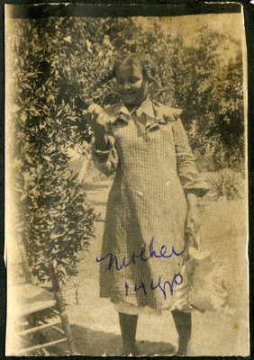 Pearl Hinds holding a hat standing next to rocking chair