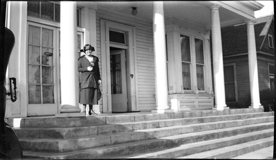 Pearl Roberts standing on front porch of A.J. Roberts, Sons & Co. Undertakers building