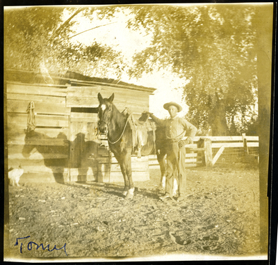 Farmhand and horse standing next shed