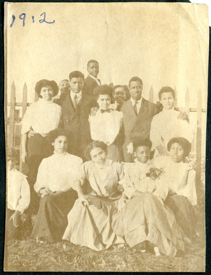 Group photograph of young men and women in front of picket fence