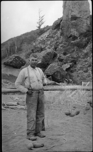 Requa: Ira Stevens at the mouth of the Klamath River, ca. 1920. Label on back in an unknown hand reads:--Ira Stevens Mouth of Klamath about 1920--Note fishnet drying poles, fishnet, and net floats