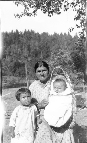 Mrs. Waukell Harry holding a baby in a basket