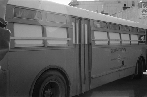 Alameda County sheriffs department school bus with arrestees showing V sign at windows