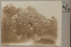 African family in front of thatched hut, Kenya