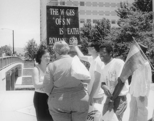 Gays around a sign with a Biblical quote