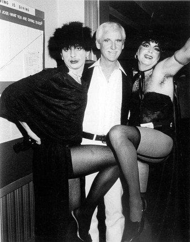 Two female impersonators posing with a man