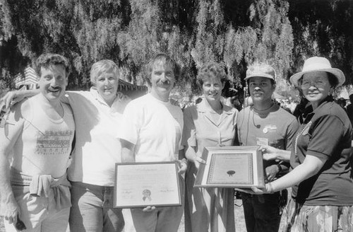 Group holding two framed proclamations