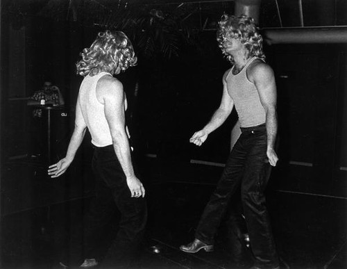 Two men wearing wigs and dancing