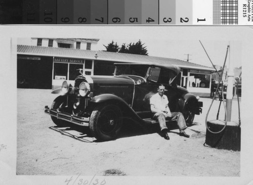 Henry Baccala in front of automobile service station, April 30, 1930