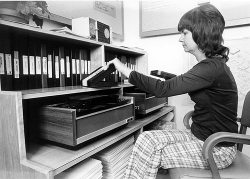 Female staff putting video tape away