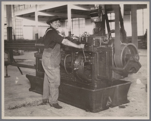 Woman in Overalls Running Machinery [ca. 1915]