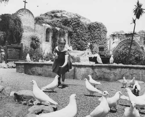 Girl feeding birds at the San Juan Capistrano Mission on the corner of Ortega Highway & Camino Capistrano