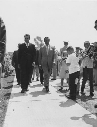 President Richard Nixon and Postmaster Hector Godinez walk through a crowd of people taking pictures