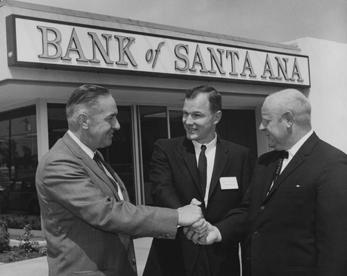 Three men shaking hands in front of Bank of Santa Ana at 17th and Louise