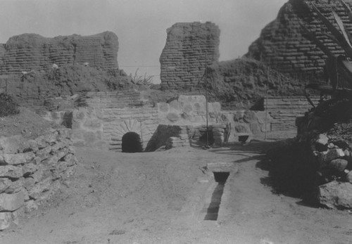 Outdoor fireplace and section of drainage system shown in foreground, Mission San Juan Capistrano