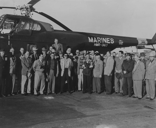 C. M. Featherly and a group of men standing alongside a Marine helicopter