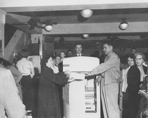 Shoppers in the appliance area of Montgomery Ward admiring a new refrigerator