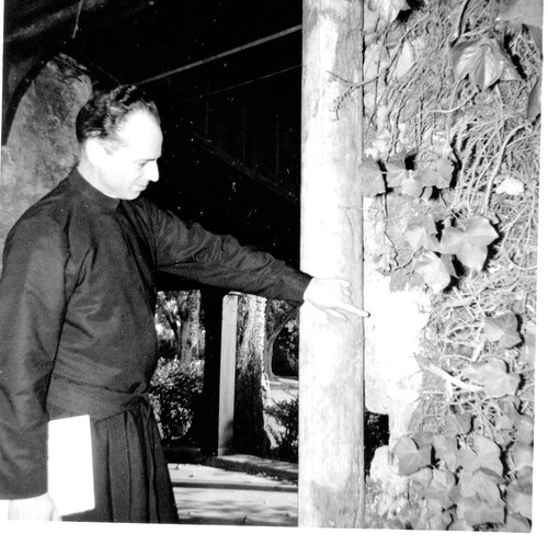 Norman Martin, S.J. pointing to section of old adobe wall