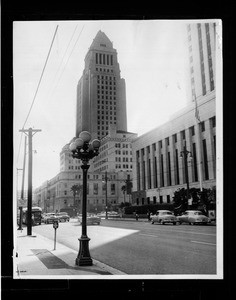 Low-angle view of Los Angeles City Hall building from across a busy street, 1959