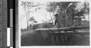 Maryknoll Sisters cross a crudely made bridge, Kaying, China, ca. 1940