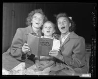 Laura, Ruth, and Lillian Wozniuk with "Phil Kerr's Gospel Songs" book at tent revival in Los Angeles, Calif., 1949