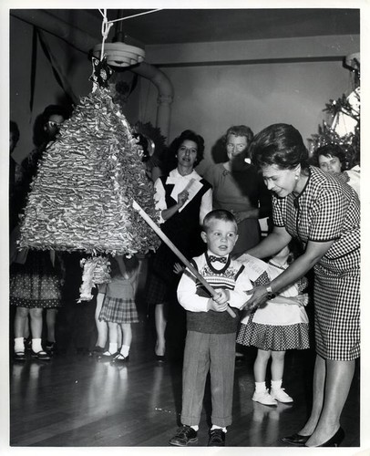 Mrs. Alfred Abram helps Barry Haycock prepare to hit a pinata