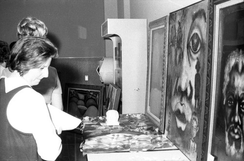Woman looks at paintings on display