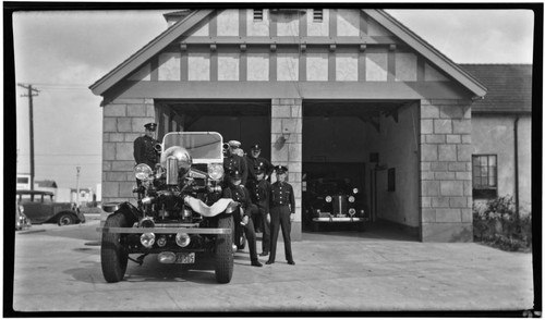 Captain and crew stand pose with Ahrens Fox engine outside Station No. 9, 3917 Long Beach Blvd