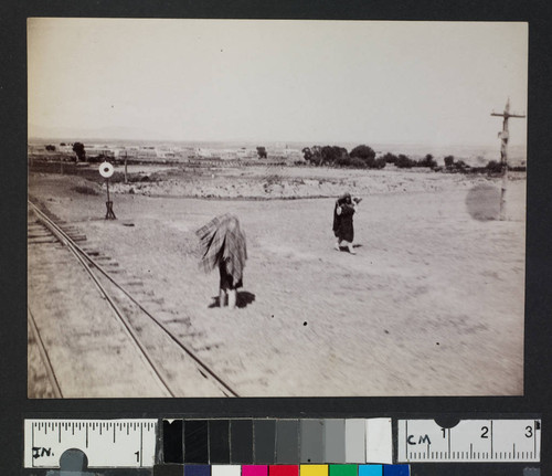 Native American women walking along railroad tracks
