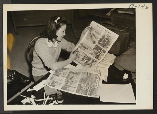 Clipping stories on their migration at this War Relocation Authority center for evacuees of Japanese ancestry. Photographer: Albers, Clem Manzanar, California